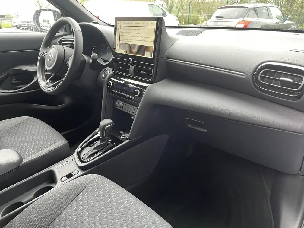 Vue intérieure côté conducteur de la Toyota Yaris Cross 1.5 Hybrid 130h, tableau de bord noir avec écran tactile central.