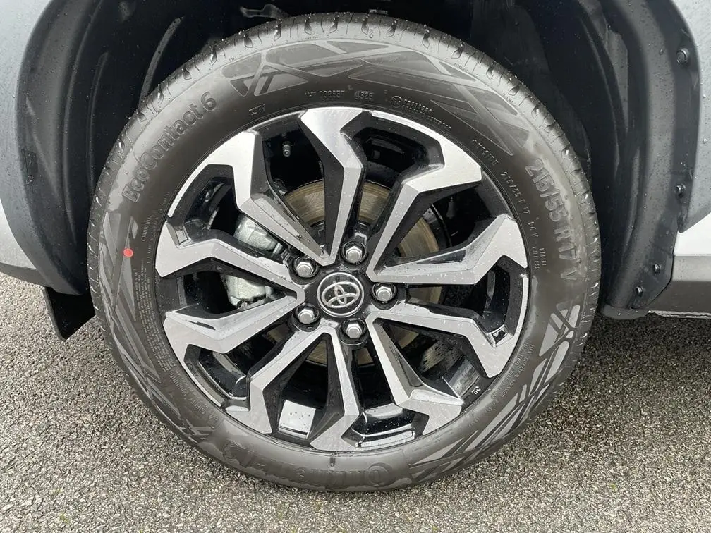 Gros plan sur la roue avant droite de la Toyota Yaris Cross gris clair avec jante alliage noire et argentée.