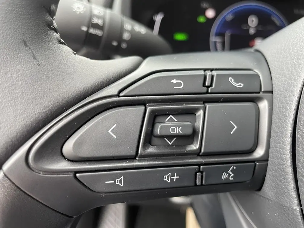Gros plan sur les commandes multifonctions noires au volant côté gauche de la Toyota Yaris Cross hybride 2026.