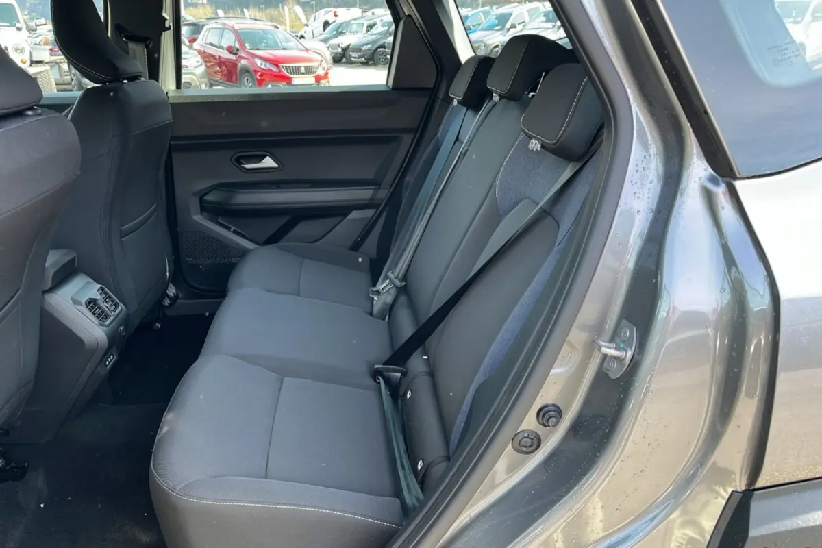 Vue intérieure côté arrière droit du Dacia Bigster gris schiste, montrant la banquette arrière en tissu avec ceintures de sécurité.