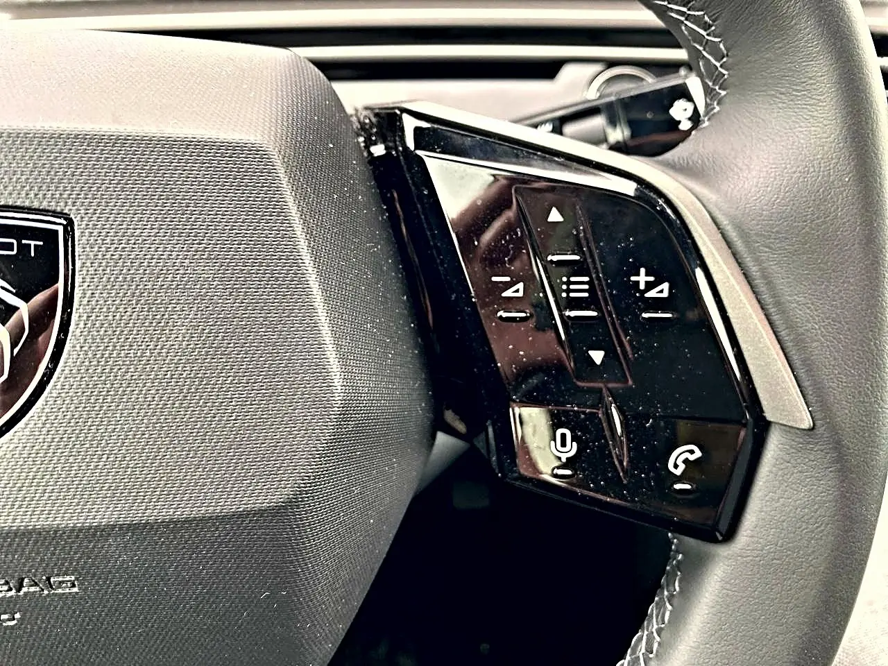 Gros plan sur le côté droit du volant cuir du Peugeot 3008 bleu 2025 avec commandes audio et téléphone intégrées.
