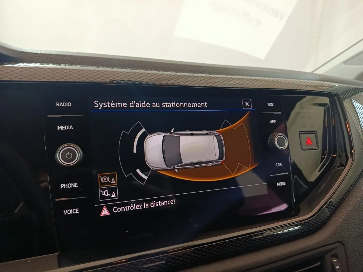 Écran tactile central du système d'aide au stationnement dans une Volkswagen Polo gris foncé, vue intérieure.
