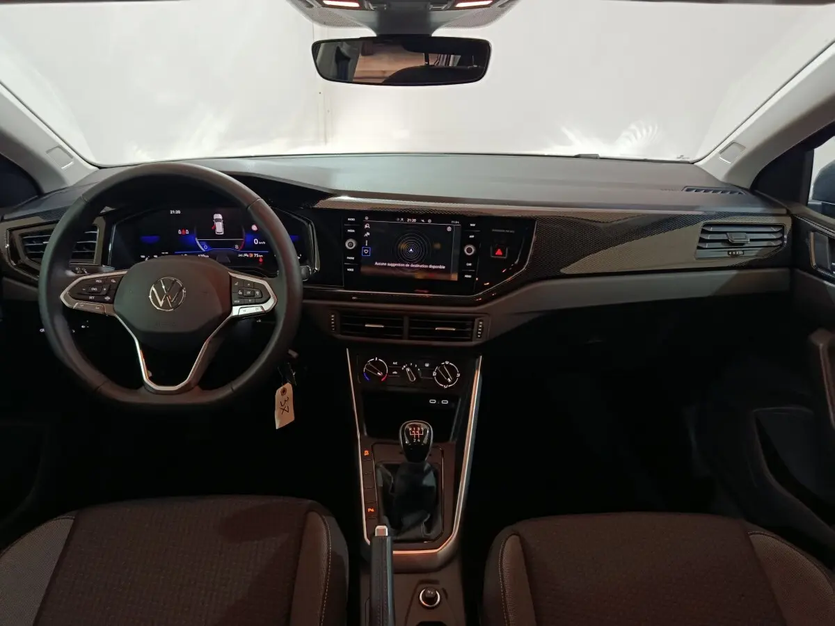 Vue intérieure frontale du tableau de bord et volant cuir de la Volkswagen Polo gris foncé avec écran tactile 8 pouces.