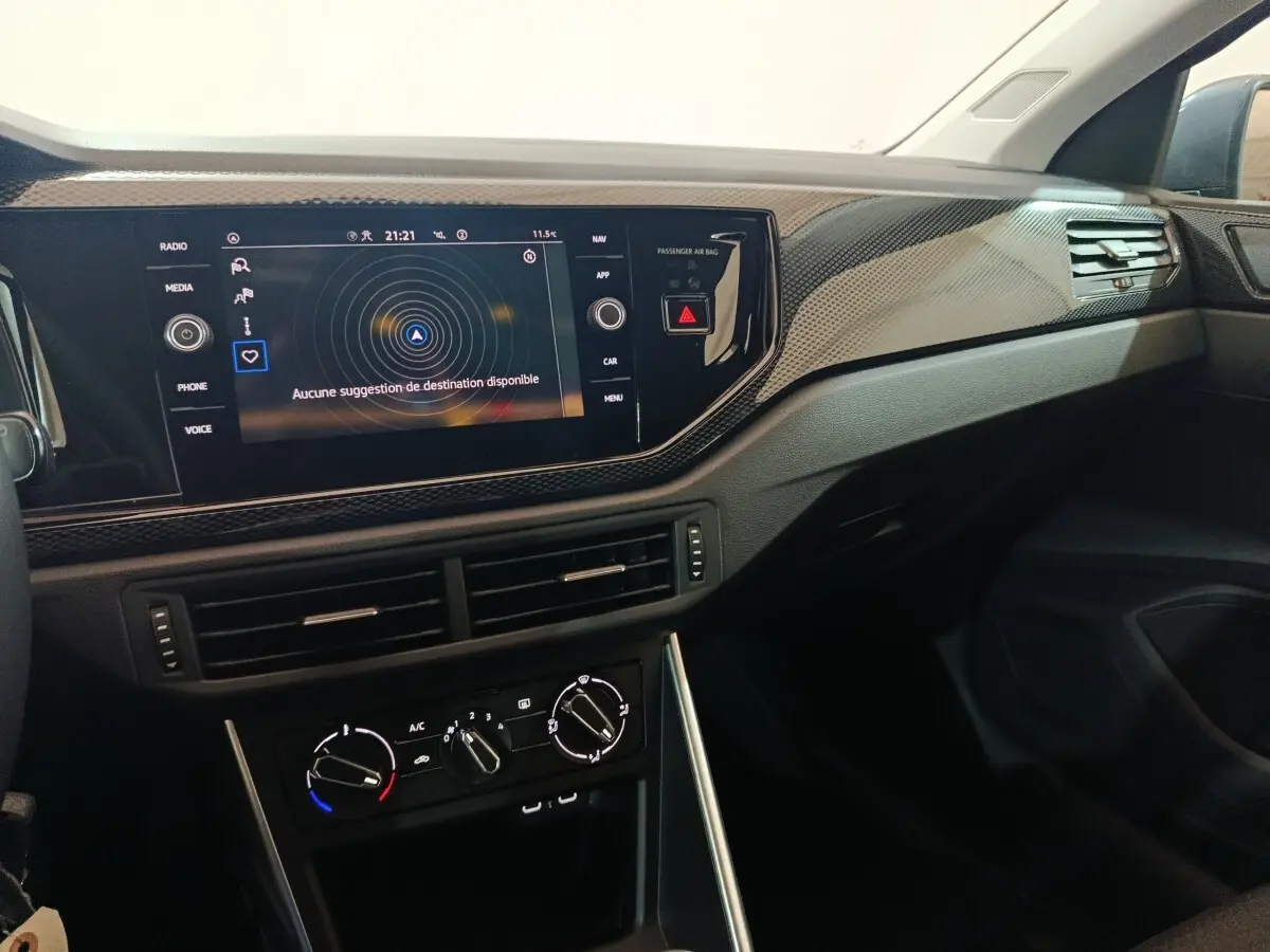 Vue intérieure côté passager du tableau de bord noir avec écran tactile 8 pouces et commandes climatisation de la Volkswagen Polo.