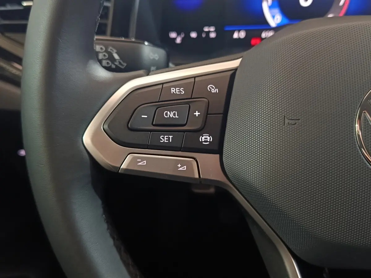 Gros plan sur la partie gauche du volant gris foncé de la Volkswagen Polo 2025 avec commandes multifonctions.