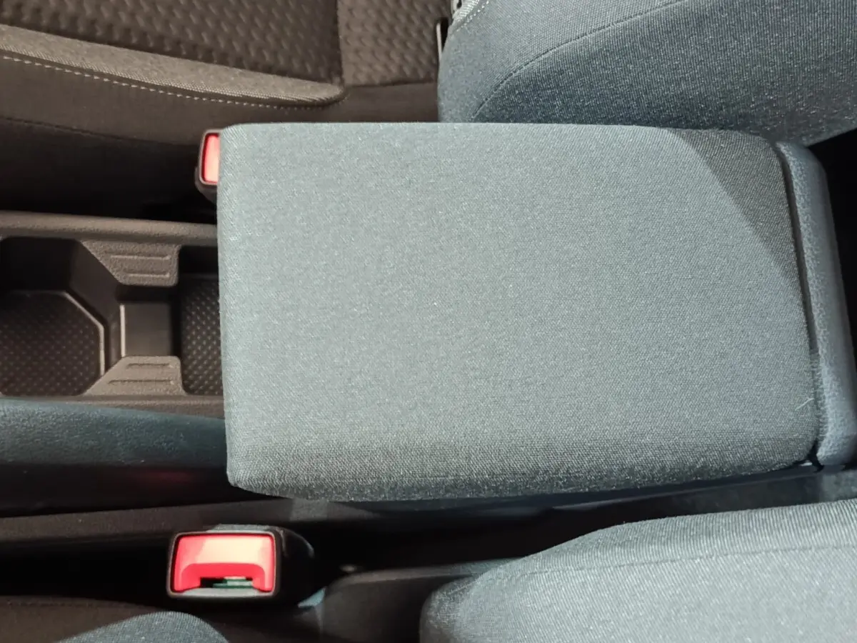 Vue rapprochée de l'accoudoir central en tissu gris foncé entre les sièges avant d'une Volkswagen Polo 2025.