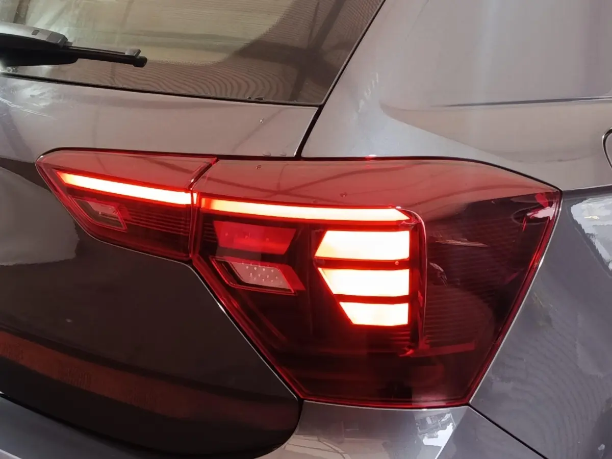 Gros plan sur le feu arrière droit allumé d'une Volkswagen Polo 2025 gris foncé, avec reflets sur la carrosserie.