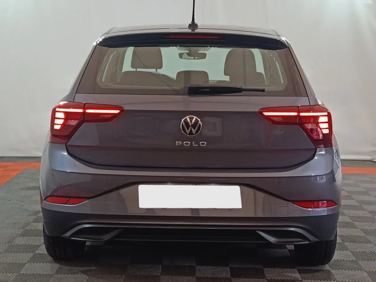 Vue arrière d'une Volkswagen Polo gris foncé 2025 avec feux arrière LED allumés dans un intérieur neutre.