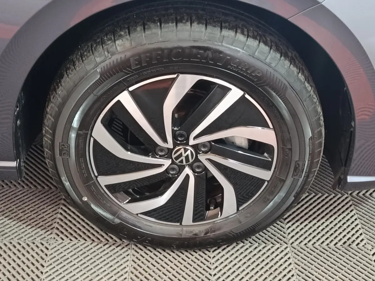Gros plan sur la roue avant droite d'une Volkswagen Polo gris foncé avec jante alliage bicolore.