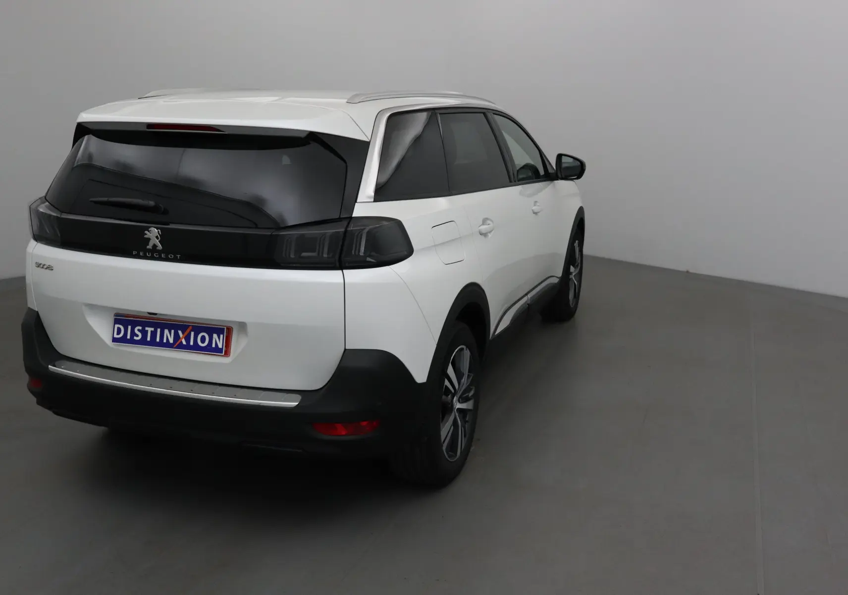 Vue 3/4 arrière droite d'un Peugeot 5008 blanc nacré avec vitres teintées et jantes alliage 18 pouces.
