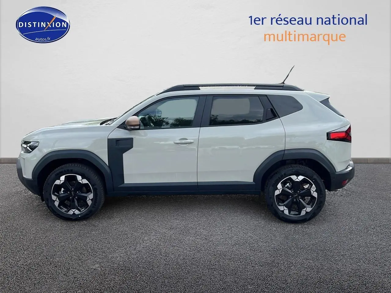 Profil latéral gauche du Dacia Duster 2025 Sandstone avec barres de toit et jantes alu noires et argentées.