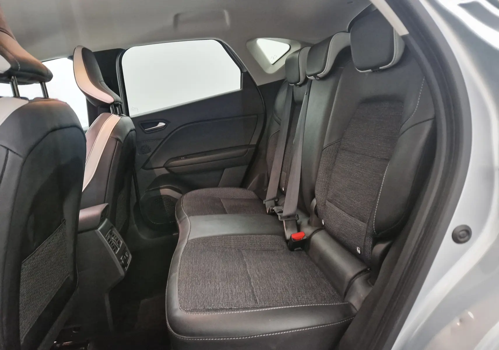 Vue intérieure côté droit sur la banquette arrière en tissu et cuir du Renault Captur 2024 gris Highland/noir.
