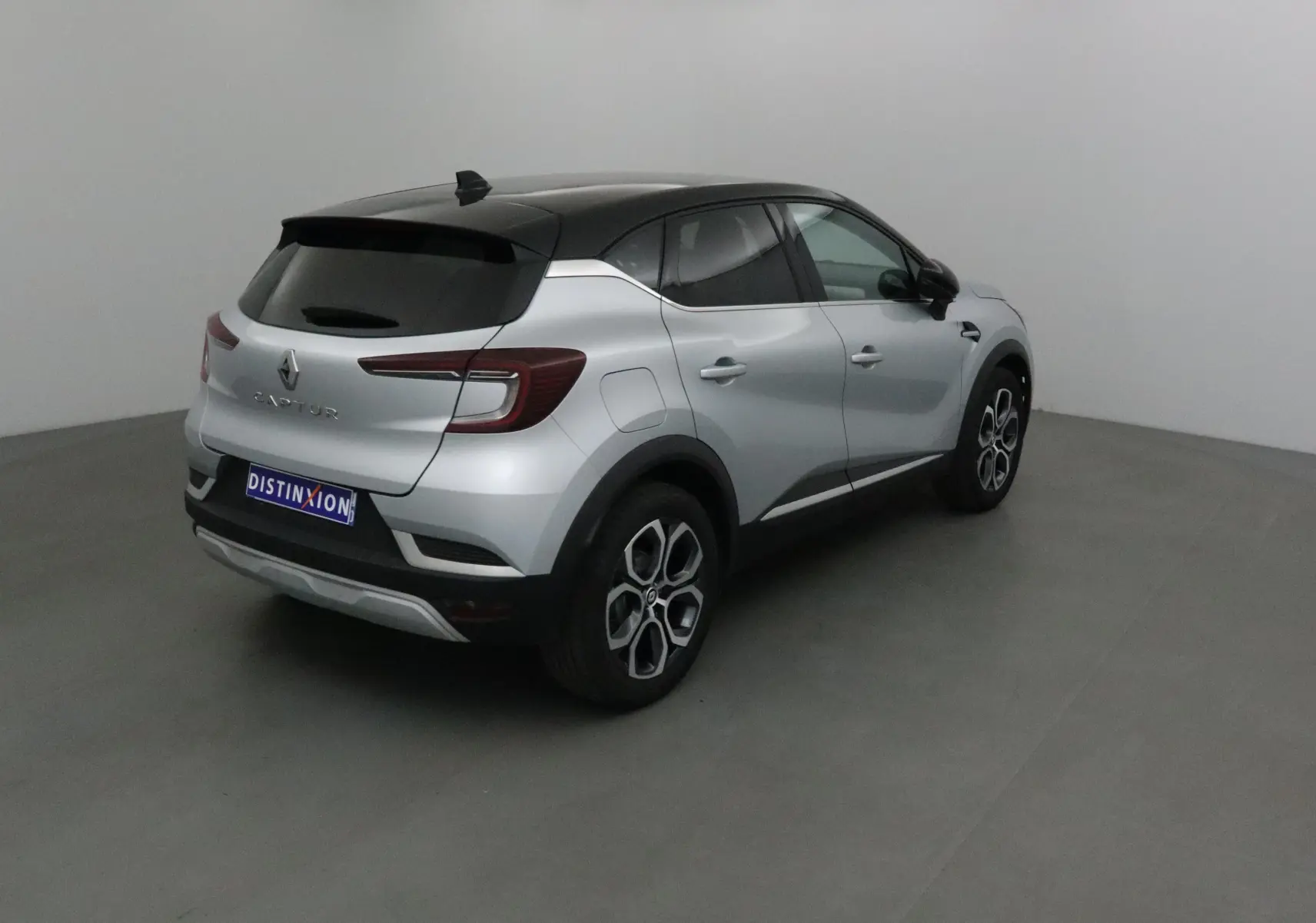 Renault Captur 2024 gris Highland avec toit noir, vu en 3/4 arrière côté droit dans un studio.