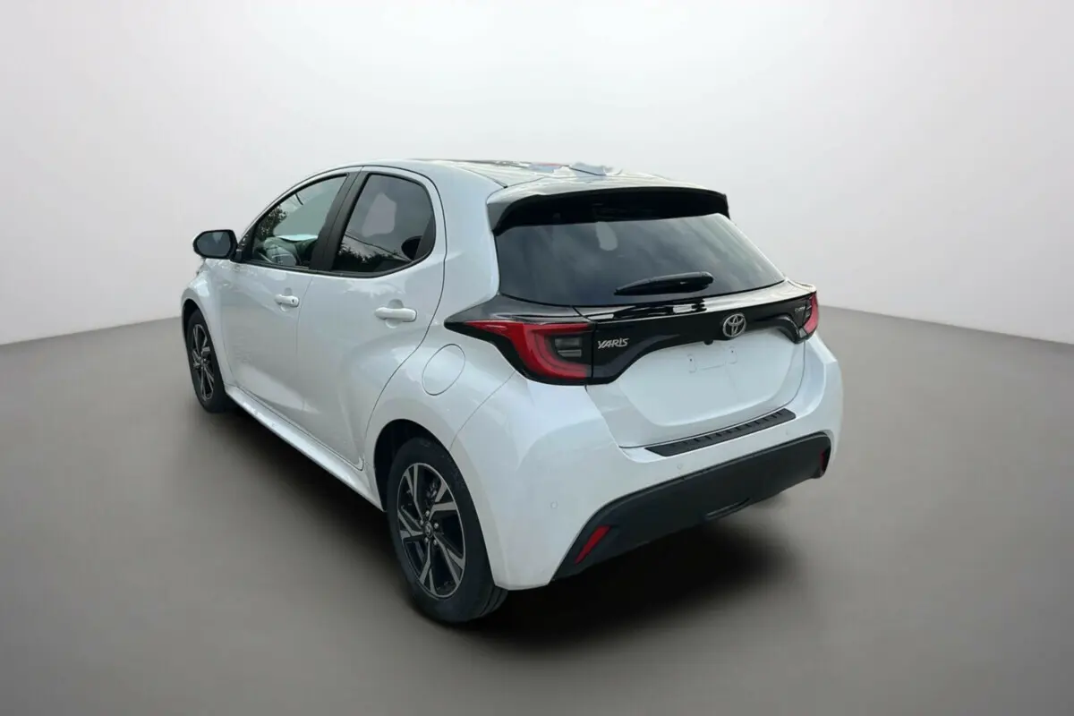 Toyota Yaris 2025 blanc lunaire vue 3/4 arrière côté gauche avec toit noir et feux arrière distinctifs.