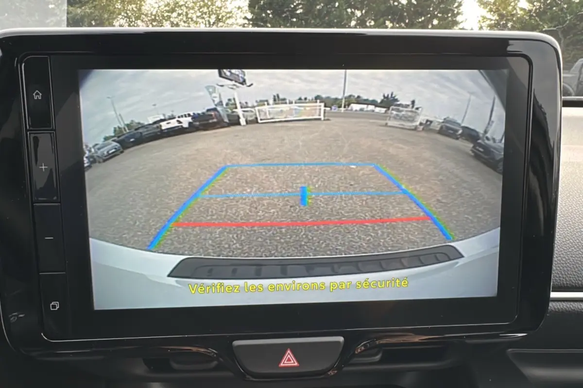 Vue caméra de recul arrière de la Toyota Yaris 2025 blanc lunaire avec lignes de guidage colorées sur écran tactile.