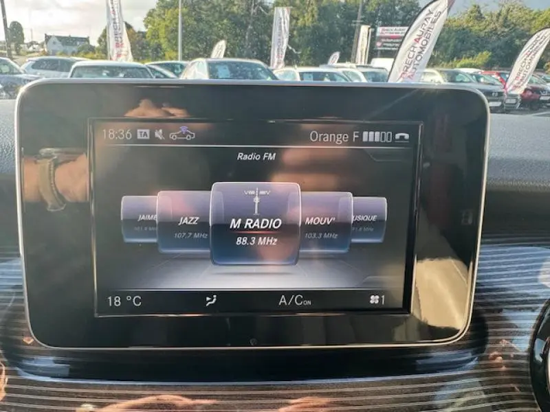 Affichage tactile central de la Mercedes Classe V 250 d blanc, montrant la radio FM avec sélection M RADIO à 88.3 MHz.