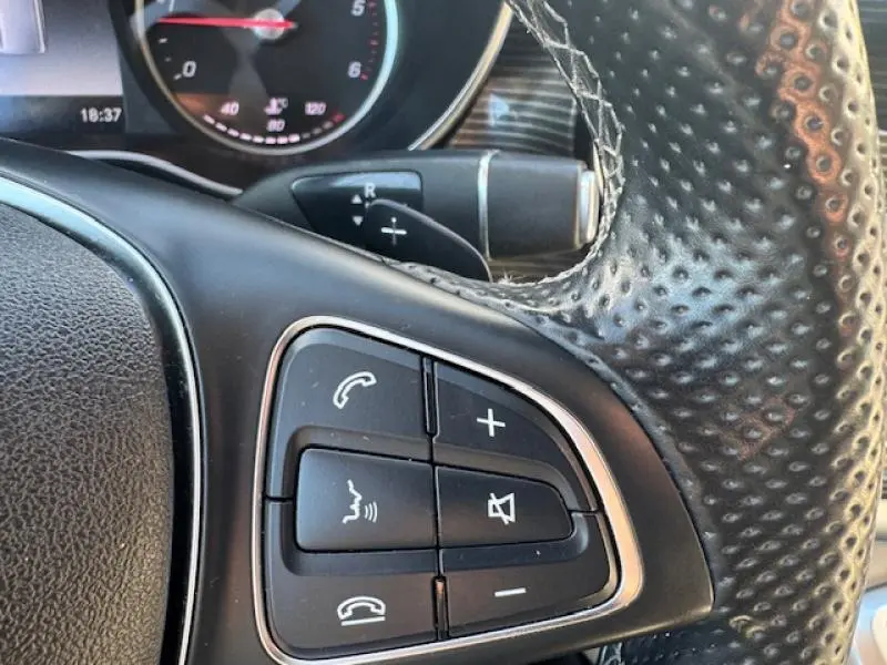 Gros plan sur les commandes du volant en cuir perforé du Mercedes Classe V 250 d blanc cristal de roche.