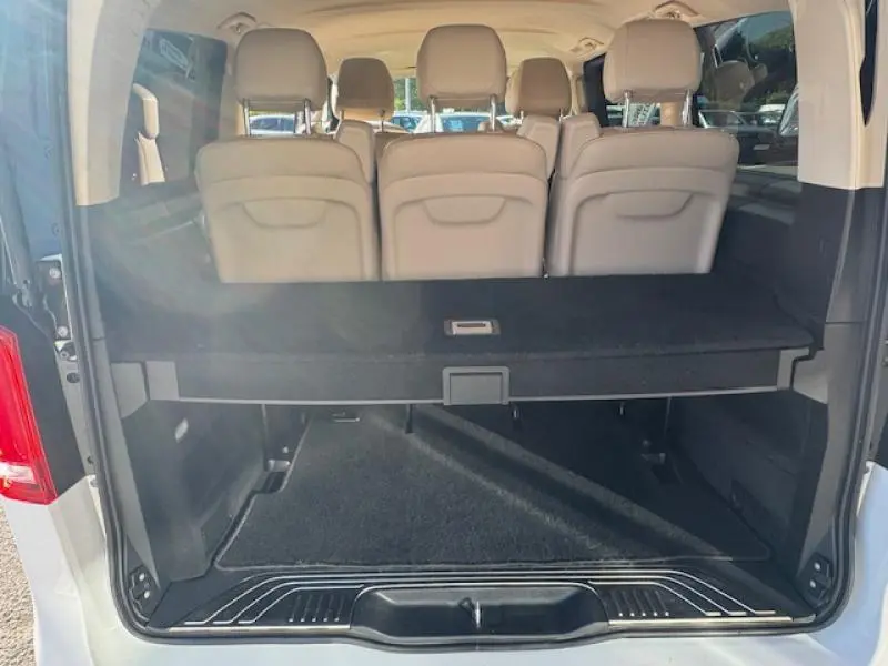 Coffre ouvert vue arrière du Mercedes Classe V blanc avec sièges beige et plancher de coffre noir.