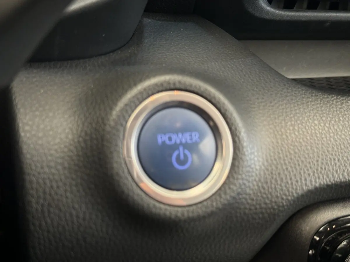 Gros plan sur le bouton de démarrage Power entouré de cuir noir dans l’habitacle de la Toyota Yaris hybride 2022.