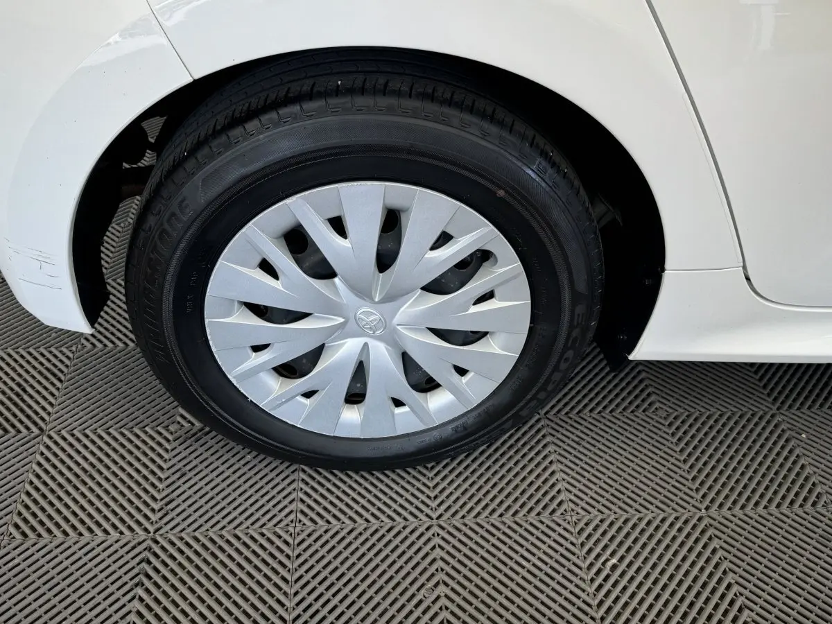 Gros plan sur la roue avant gauche blanche d'une Toyota Yaris hybride 2022 avec enjoliveur argenté et carrosserie blanche.