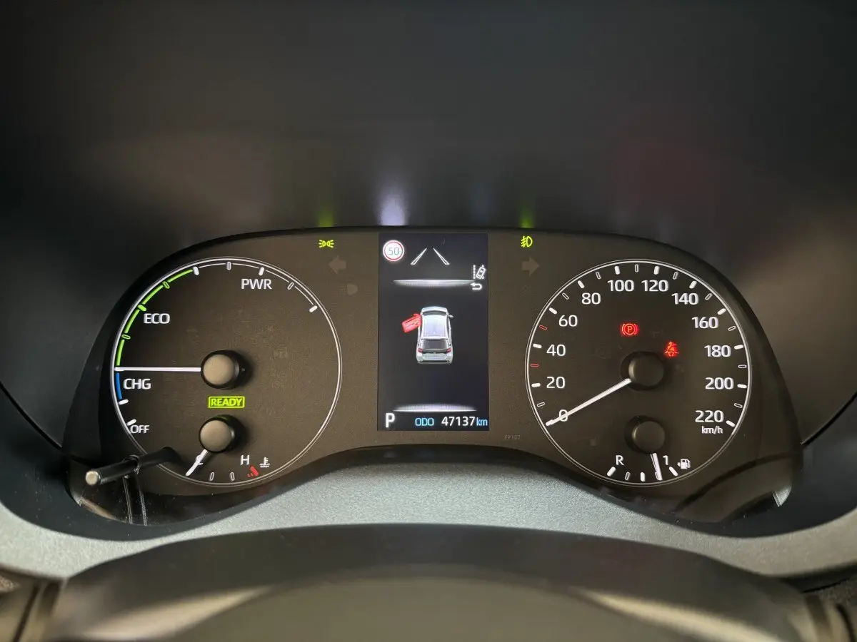 Vue rapprochée du tableau de bord numérique de la Toyota Yaris hybride 2022 avec affichage des compteurs et alertes.