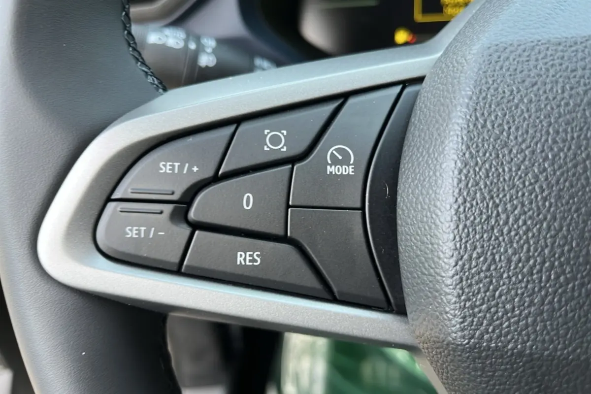 Gros plan sur les commandes du régulateur de vitesse au volant cuir du Dacia Bigster Hybrid 155 Expression Plus.