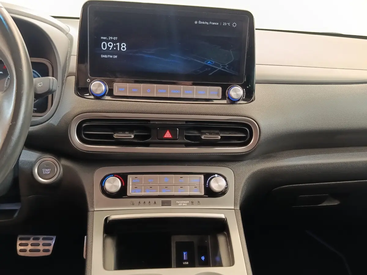 Vue intérieure du tableau de bord du Hyundai Kona électrique 2023 avec écran tactile central et commandes climatisation.
