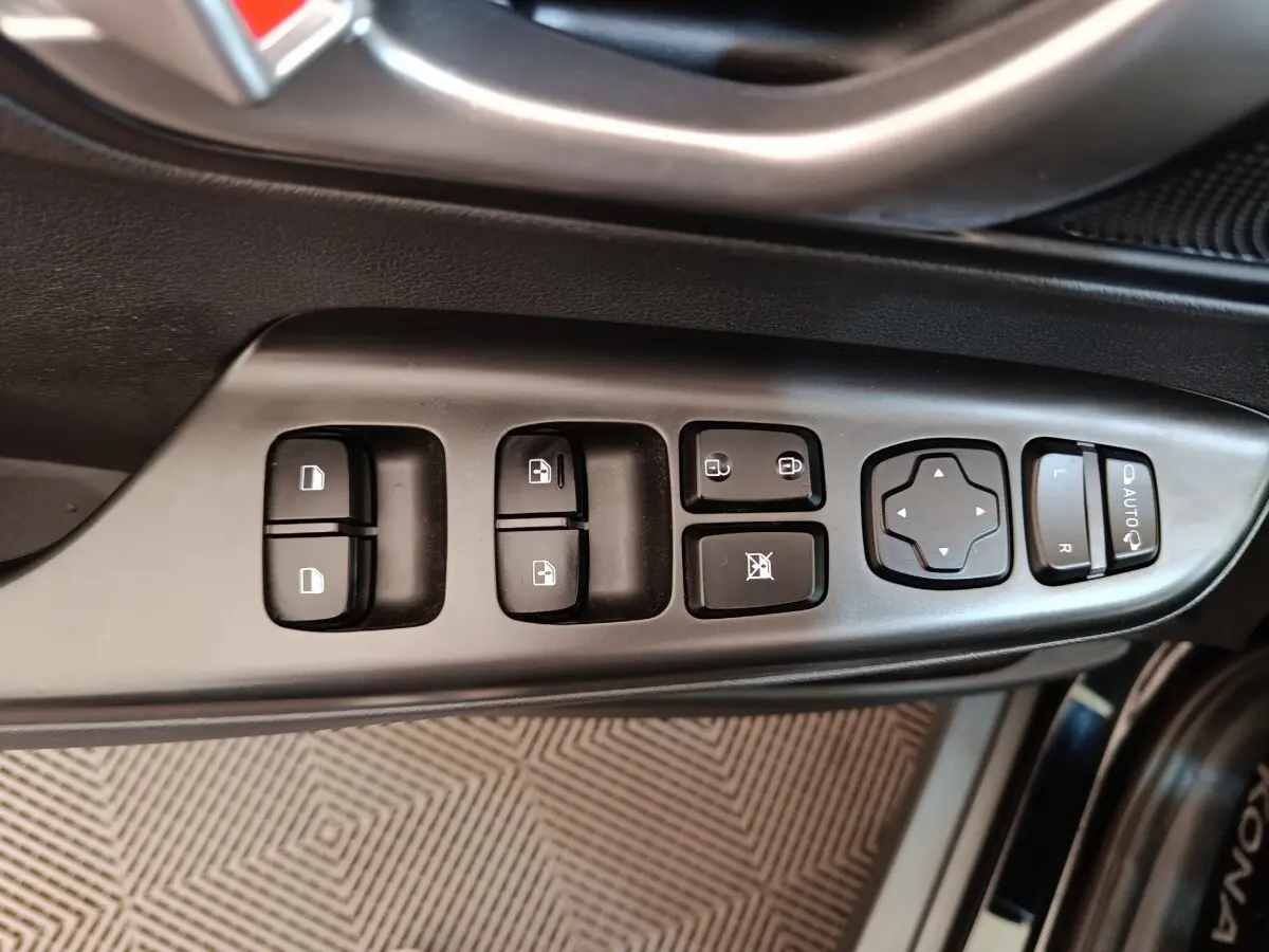 Vue rapprochée des commandes de porte côté conducteur du Hyundai Kona noir électrique 2023, avec boutons de vitres et rétroviseurs.