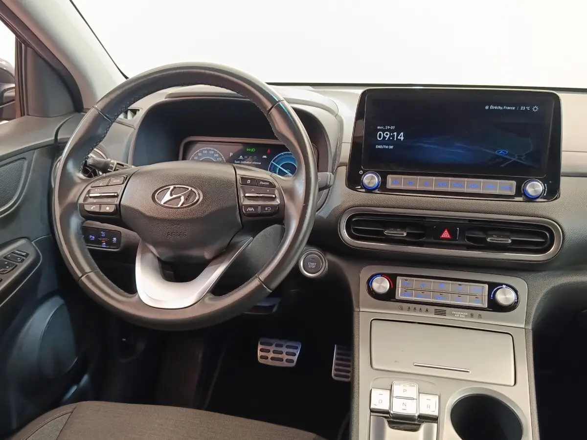 Vue intérieure avant du tableau de bord et volant cuir de la Hyundai KONA électrique 2023 avec écran tactile central.