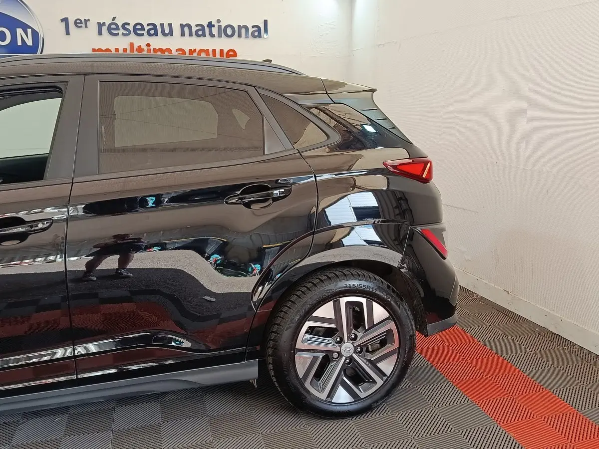 Vue latérale arrière droite d'un Hyundai Kona électrique noir, mettant en valeur la roue et les feux arrière LED.