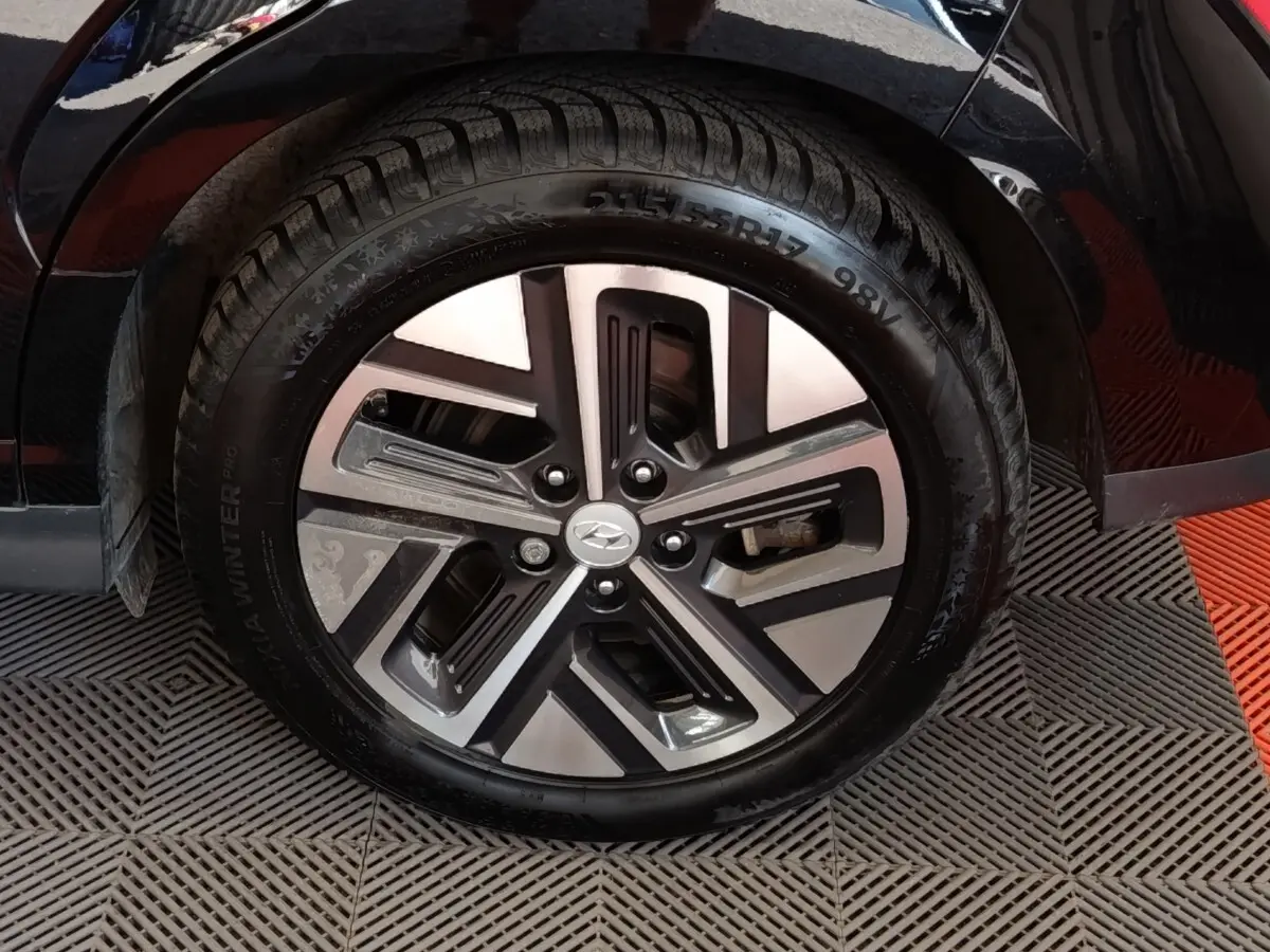 Gros plan sur la roue avant droite noire d’un Hyundai Kona électrique 2023 avec jante alliage bicolore.