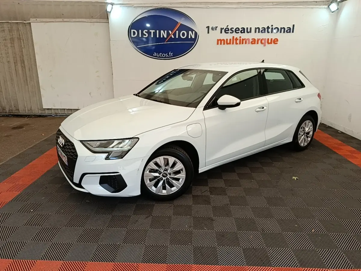 Audi A3 40 TFSI e blanc en 3/4 avant droit, hybride rechargeable, avec jantes alliage et prise de charge visible côté avant gauche.