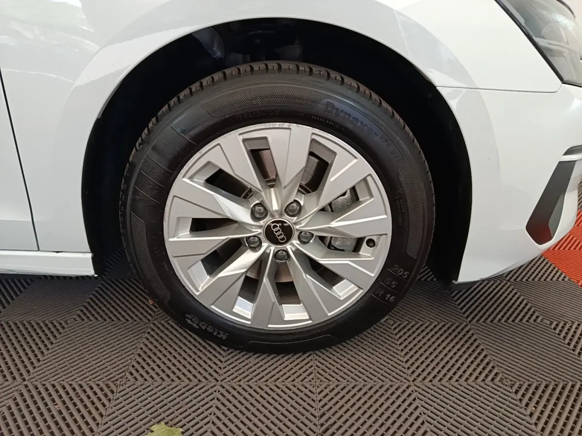 Gros plan sur la roue avant droite d’une Audi A3 blanche, mettant en valeur la jante en alliage et le pneu.