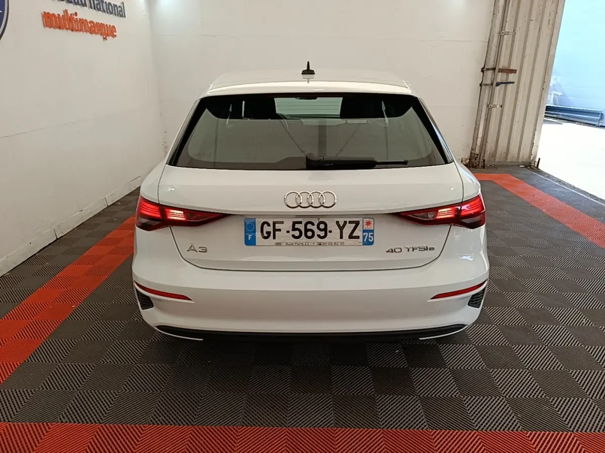 Vue arrière d'une Audi A3 blanche 40 TFSI e 2022 avec feux LED allumés dans un garage fermé.