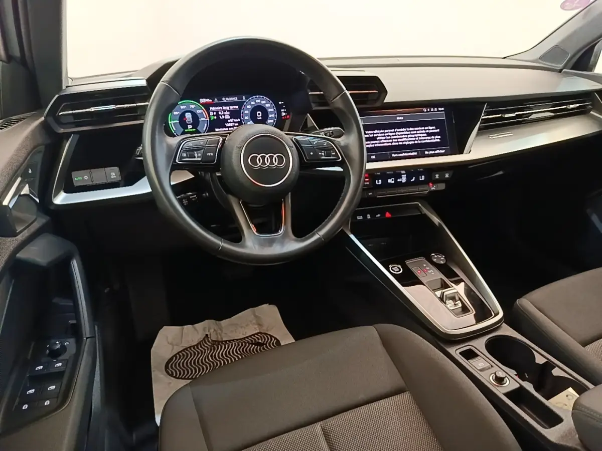 Vue intérieure avant de l'Audi A3 40 TFSI e 2022, volant cuir multifonctions et grand écran tactile central.