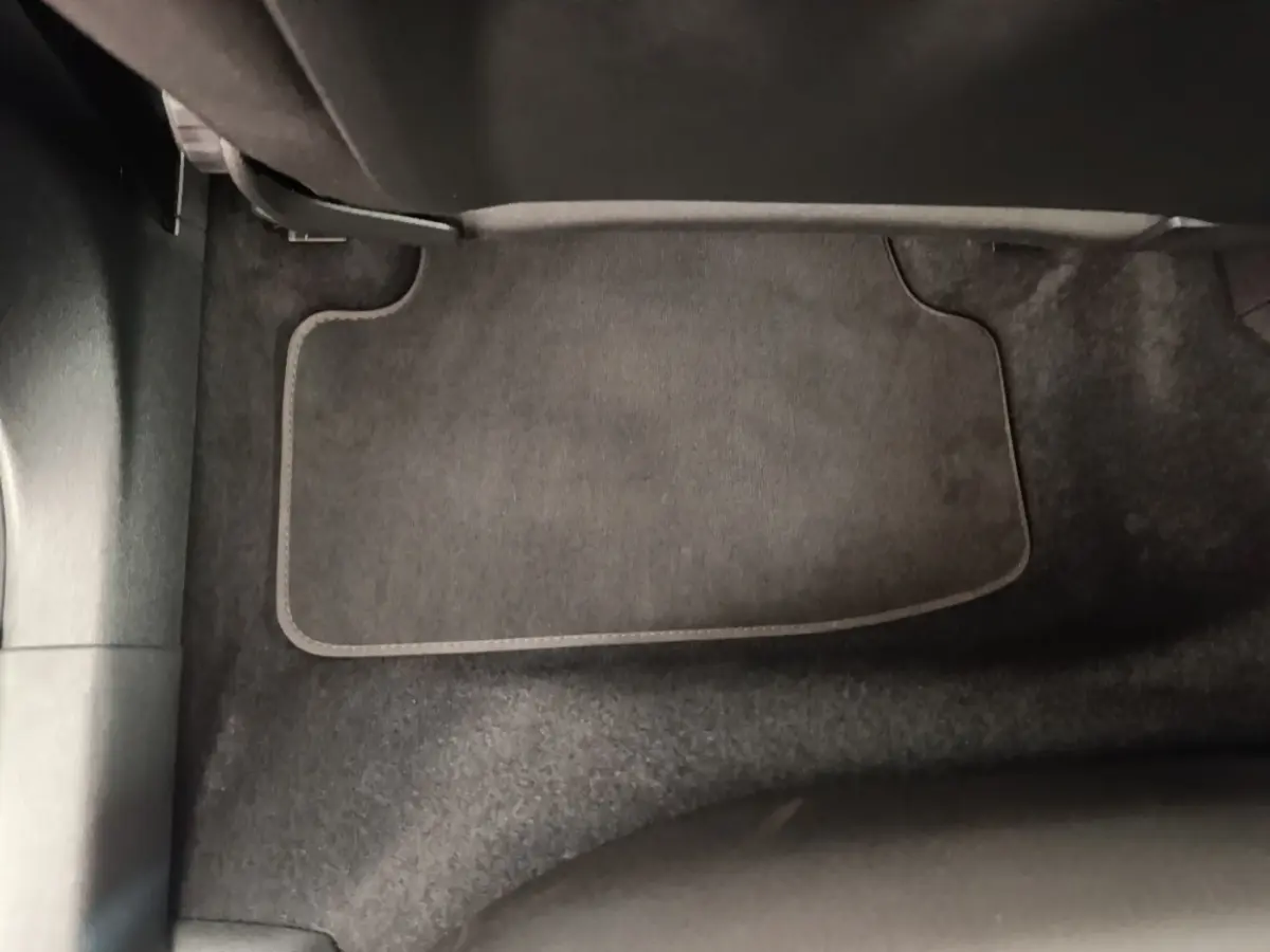 Vue rapprochée du tapis de sol noir côté passager avant de l'Audi A3 40 TFSI e blanc, intérieur sobre et propre.