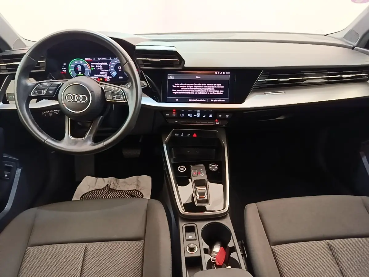 Vue intérieure avant de l'Audi A3 40 TFSI e 2022, tableau de bord noir avec écran tactile et volant cuir multifonctions.