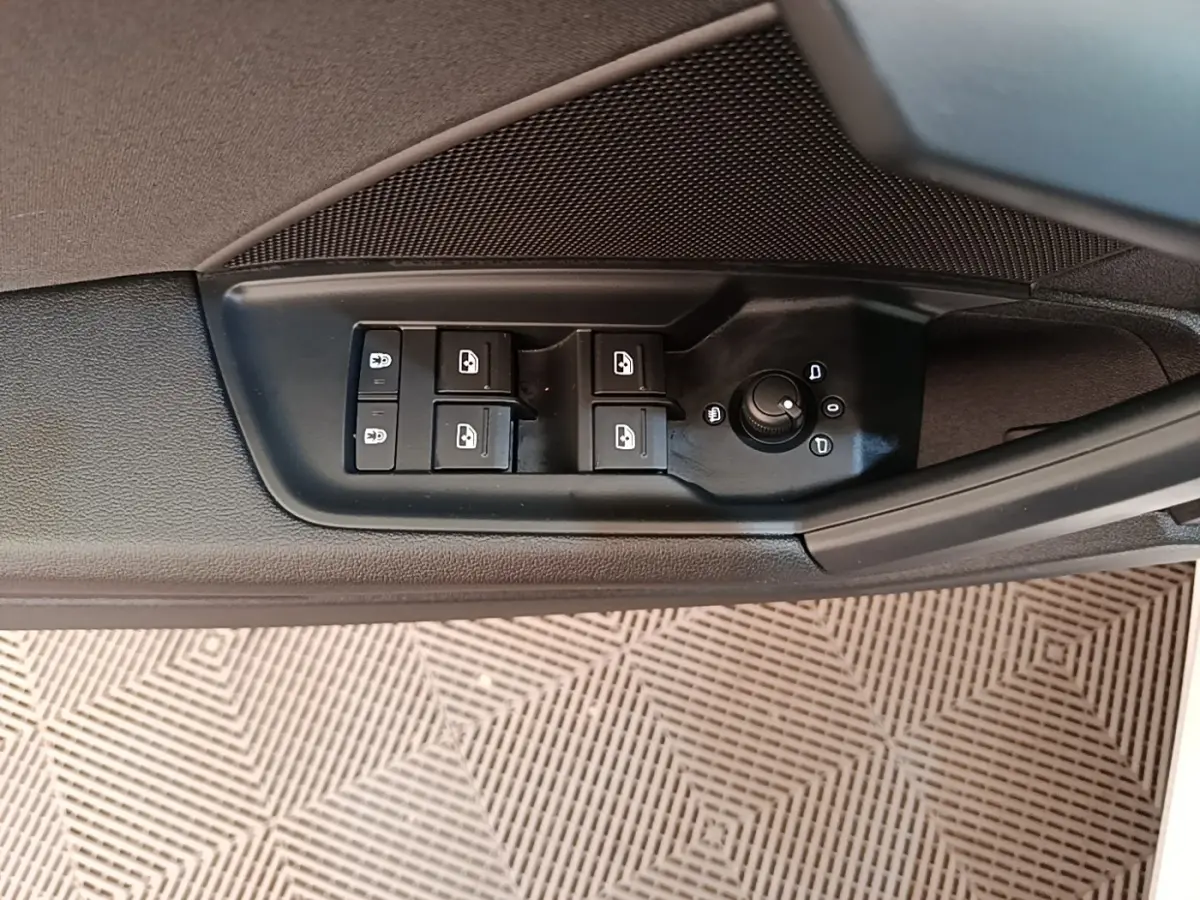 Gros plan sur les commandes de lève-vitres et réglage des rétroviseurs côté conducteur d'une Audi A3 blanche.