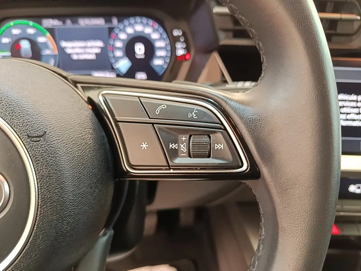 Gros plan sur le volant cuir noir de l'Audi A3 40 TFSI e 2022 avec commandes multimédia intégrées à droite.