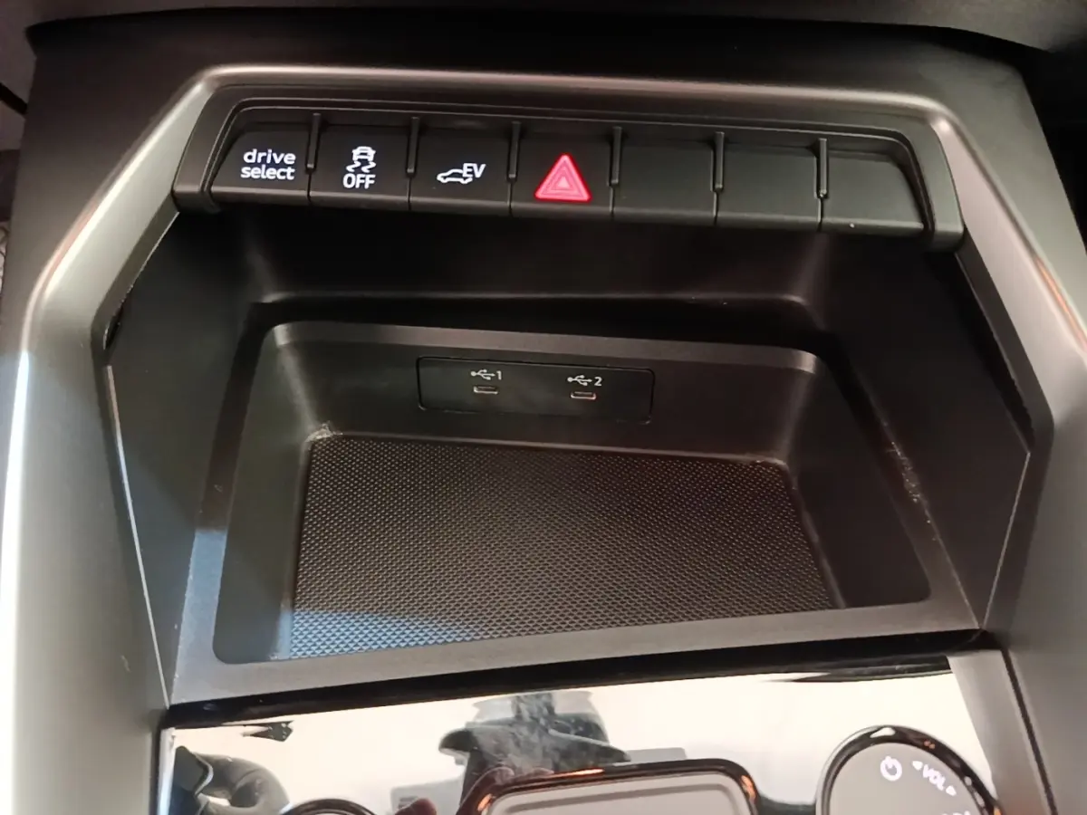 Gros plan sur la console centrale noire de l’Audi A3 40 TFSI e 2022, avec boutons de contrôle et ports USB visibles.