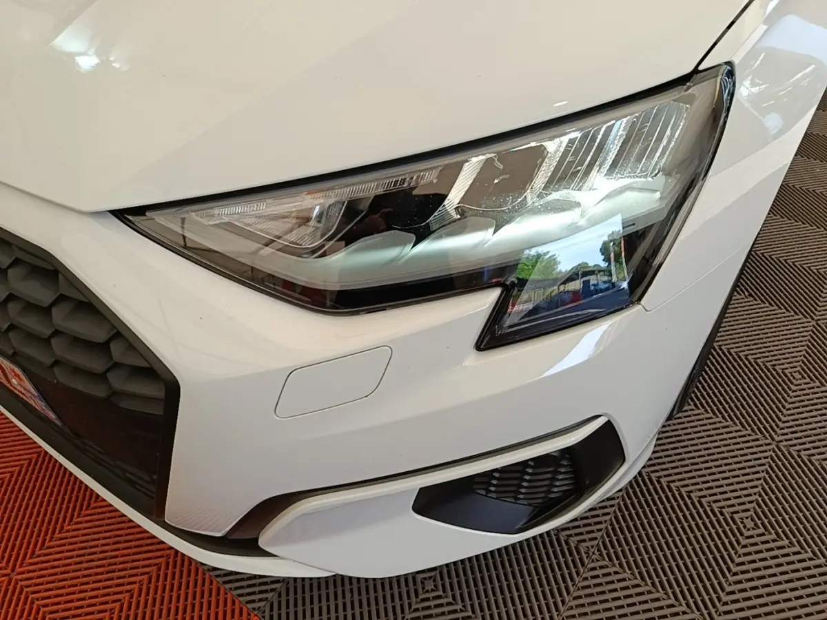 Gros plan sur l'avant droit blanc d'une Audi A3 40 TFSI e 2022, mettant en valeur le phare LED et la calandre noire.