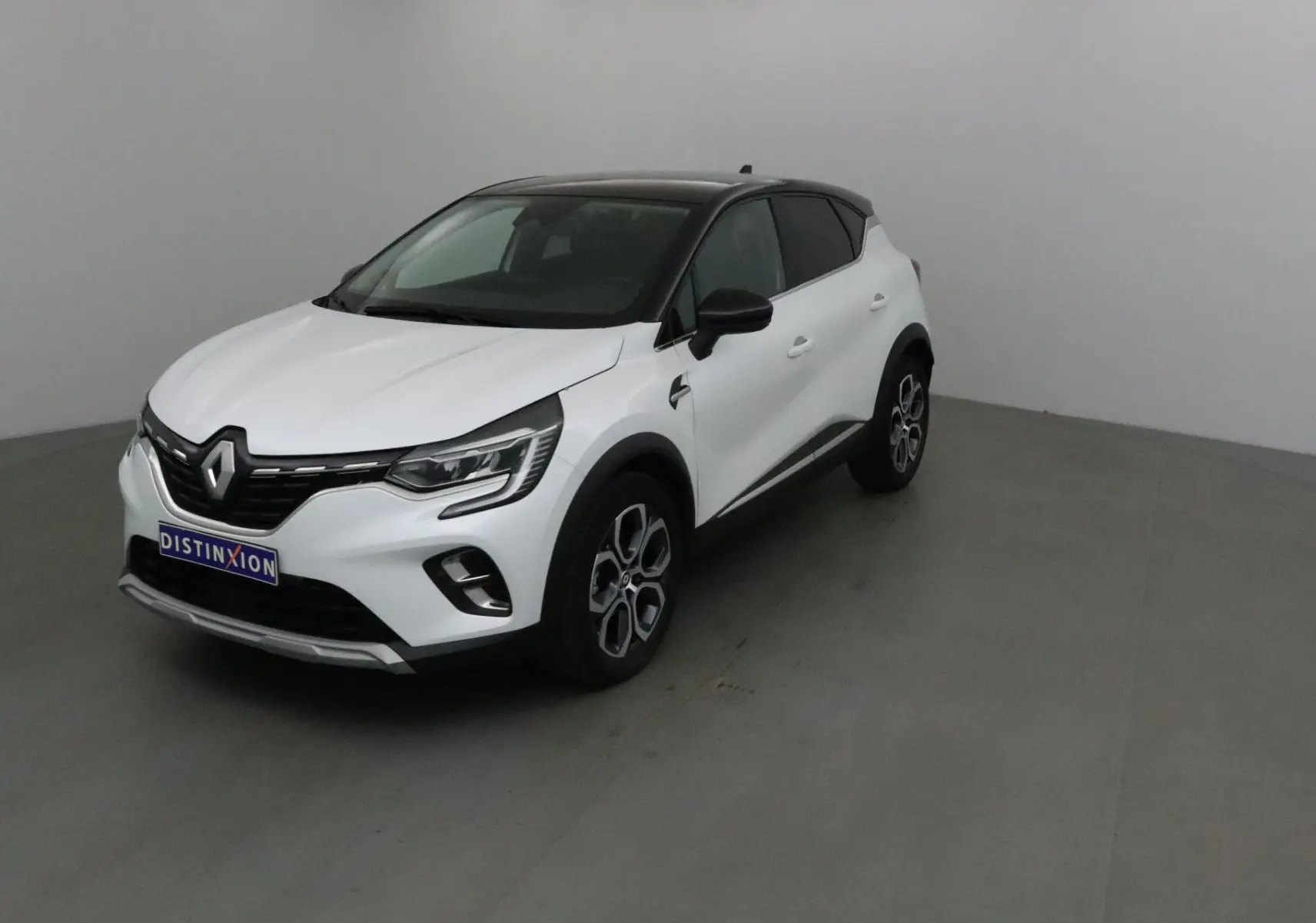 Renault Captur blanc nacré avec toit noir, vu en 3/4 avant droit dans un studio neutre.