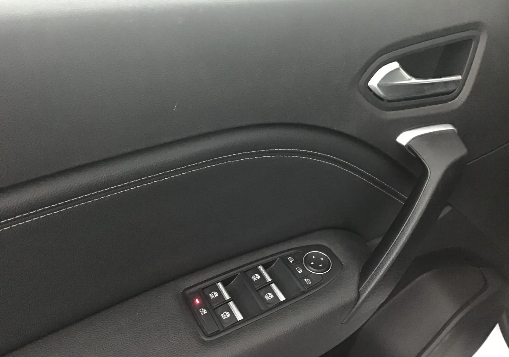 Gros plan sur la porte côté gauche du Renault Captur blanc nacré, mettant en valeur les commandes électriques des vitres et la poignée noire.