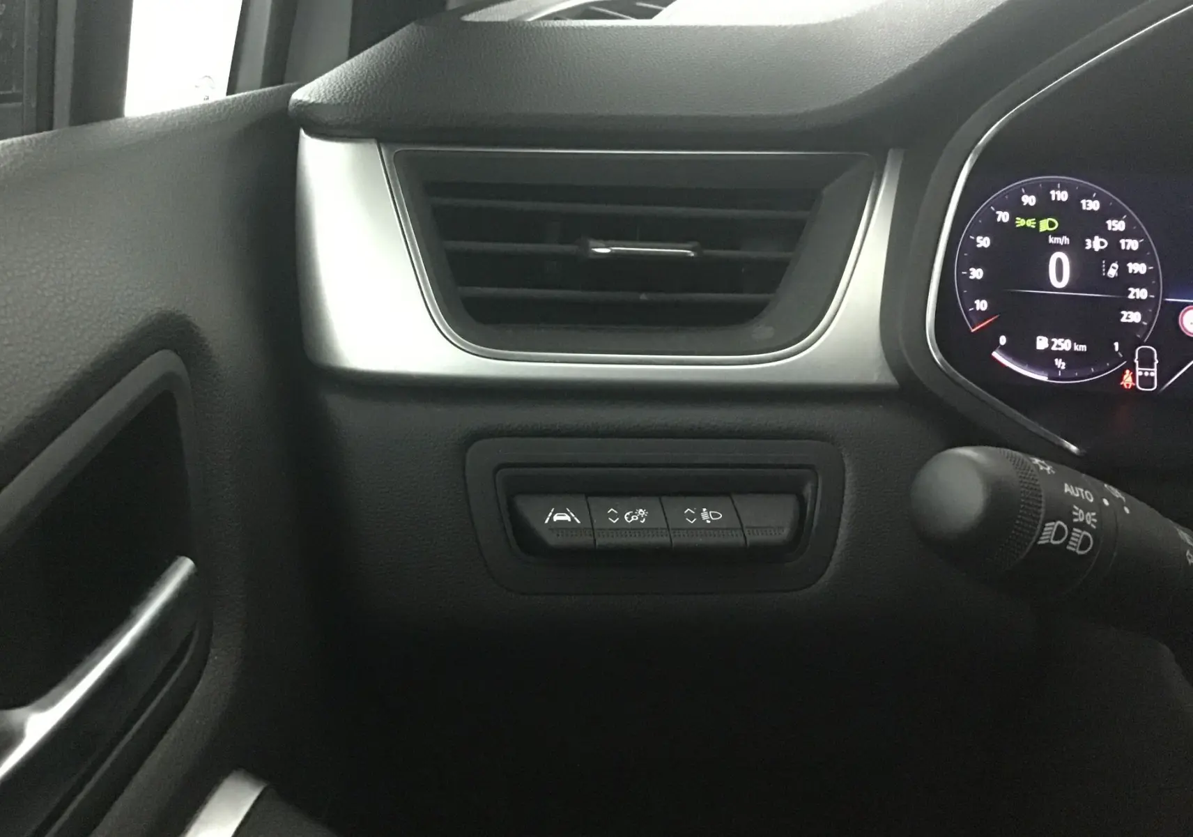 Détail du tableau de bord côté gauche du Renault Captur 2024 blanc nacré, avec commandes d'assistance et ventilation.