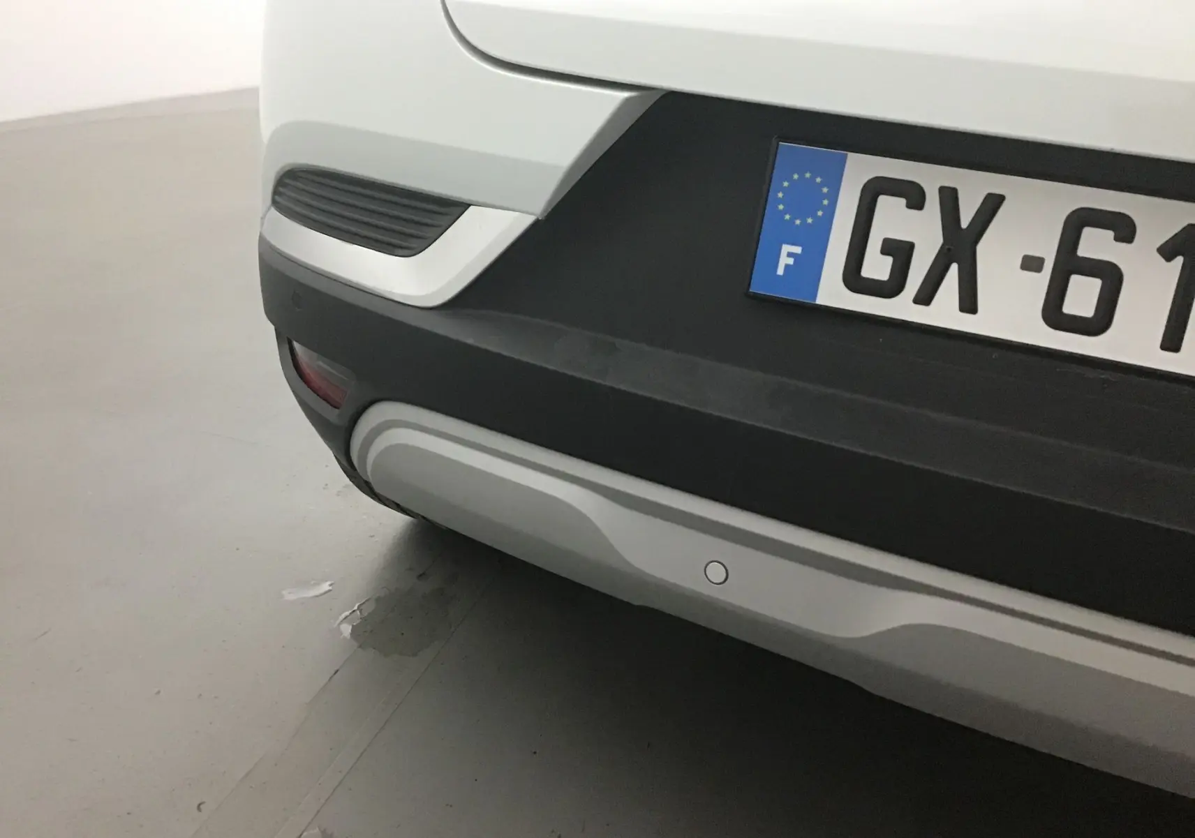 Gros plan sur le pare-chocs arrière blanc nacré du Renault Captur 2024 avec plaque d'immatriculation française visible.