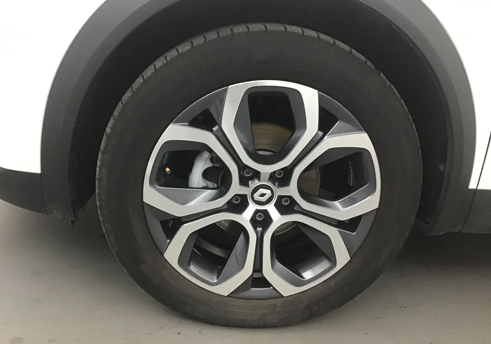 Gros plan sur la roue avant gauche du Renault Captur blanc nacré avec jante alliage 18 pouces au design moderne.