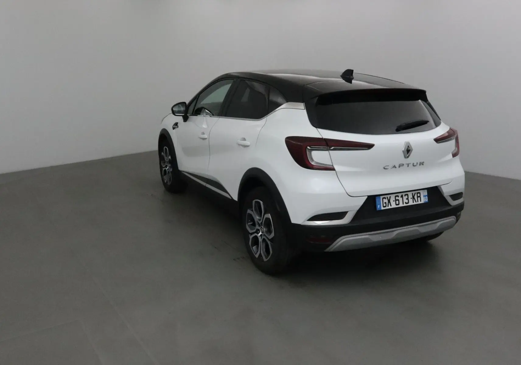 Renault Captur blanc nacré et toit noir vu en 3/4 arrière droit, avec feux arrière LED et jantes alliage 18 pouces.