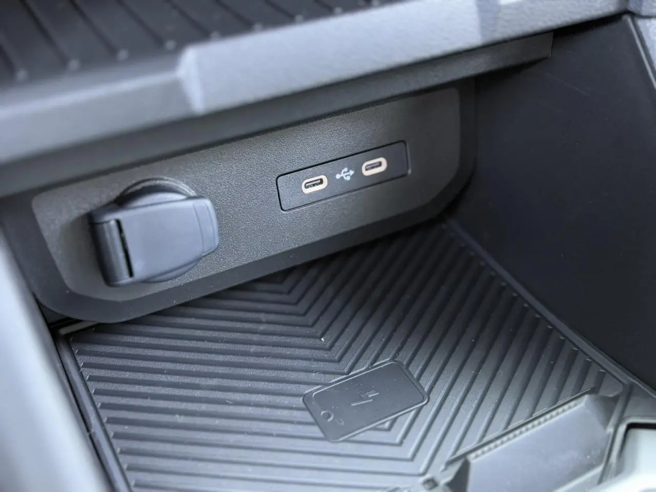Gros plan sur la console centrale du Dacia Duster 2025 montrant les ports USB-C et le chargeur à induction noir.