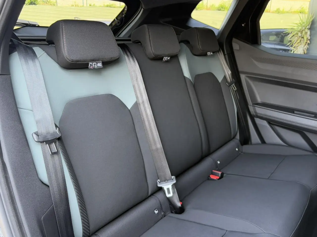 Banquette arrière en tissu bicolore gris et noir du Dacia Duster 2025 vue côté droit, avec ceintures de sécurité visibles.