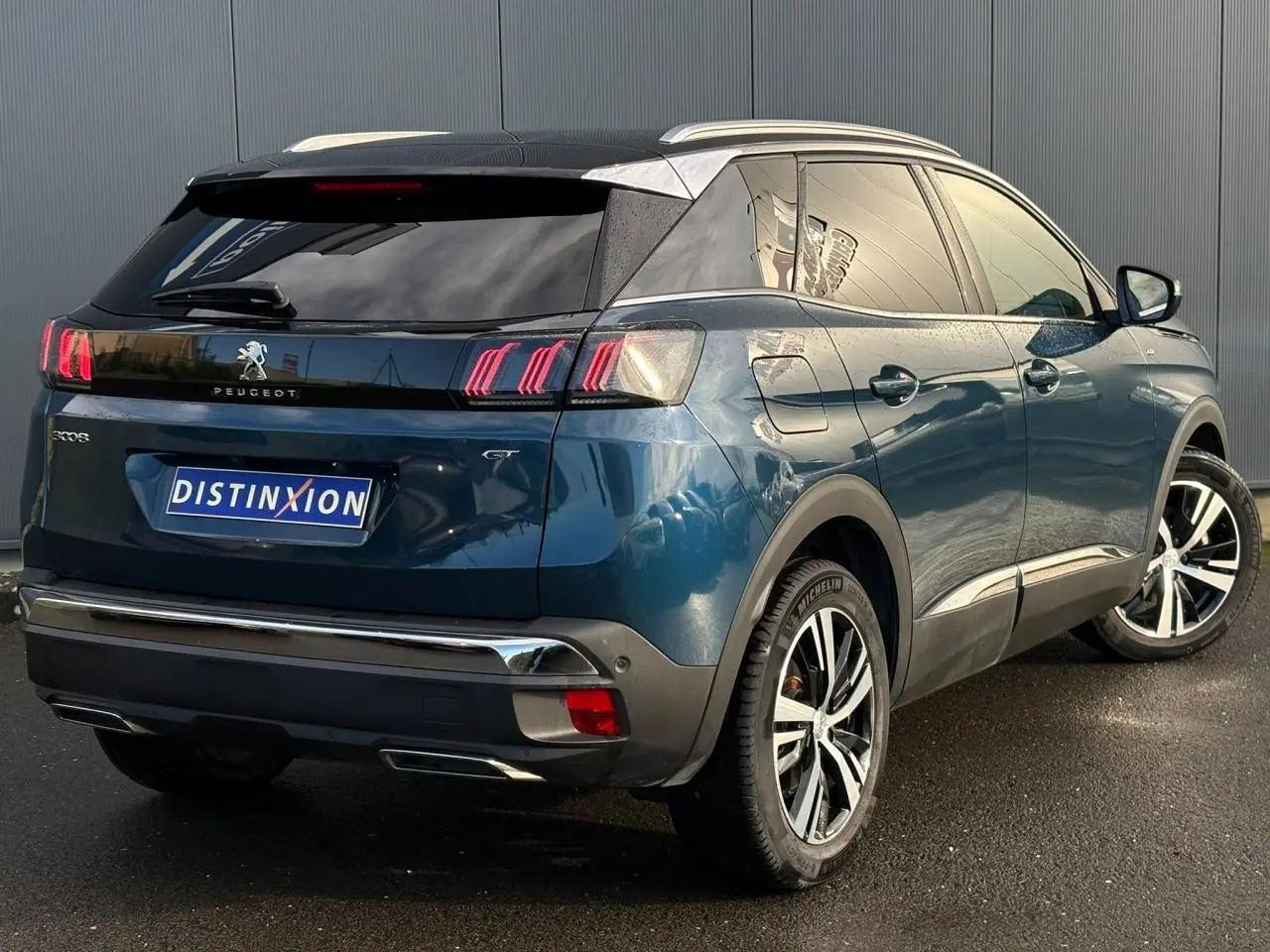Vue 3/4 arrière droite du Peugeot 3008 GT 2023 bleu Célèbes avec toit noir et jantes alliage bi-ton.